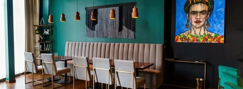 Cariño dining room with a teal wall, banquette and Frida Kahlo portrait