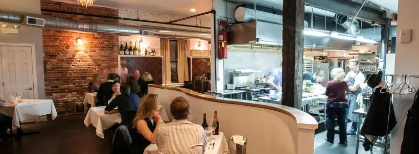 Diners seated beside an open restaurant kitchen