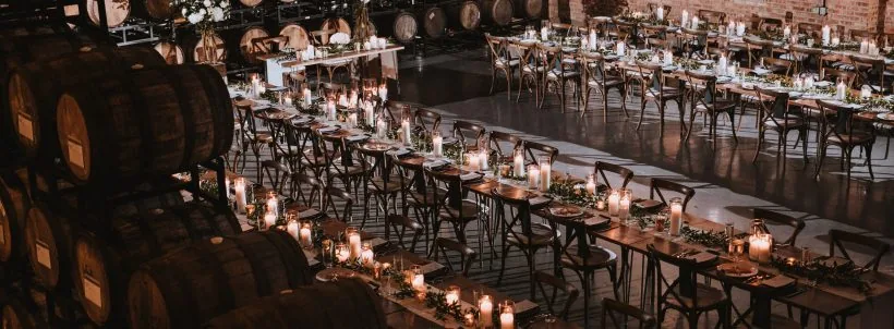 Tables set for an event beside stacked brewery barrels